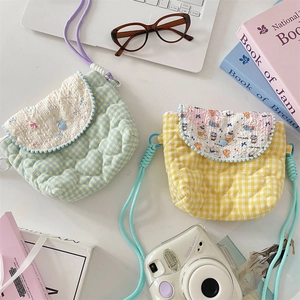 Detail view of quilted heart pattern and plush white ball trim on mini crossbody bags