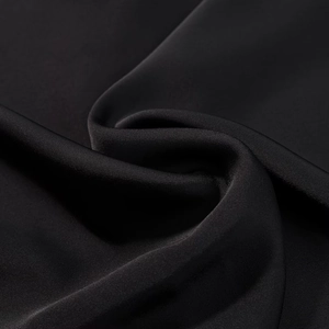 Macro di tessuto tessile nero liscio che mostra la trama della seta e il drappeggio