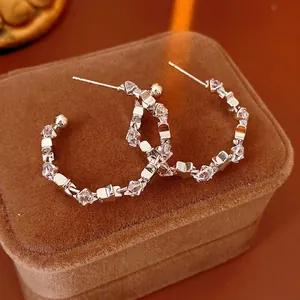 Elegant silver C-shaped hoop earrings with sparkling cubic zirconia on a velvet display