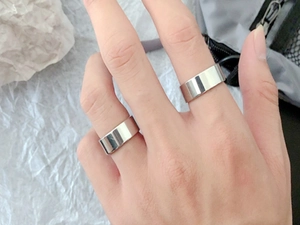 Close-up of unisex minimalist silver titanium steel rings worn on fingers with a polished finish