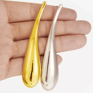 Macro detail of oversized teardrop earrings in polished gold and silver finishes