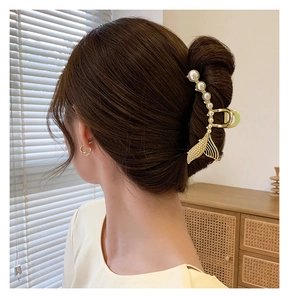 Détail d'une pince à cheveux queue de poisson dorée avec perles blanches sur modèle