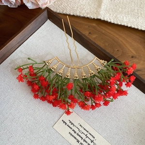 Detailed close-up of a golden floral hair pin with red star-shaped flower clusters