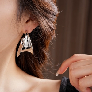 Close-up of a model wearing chunky silver C-shape earrings with a polished mirror finish