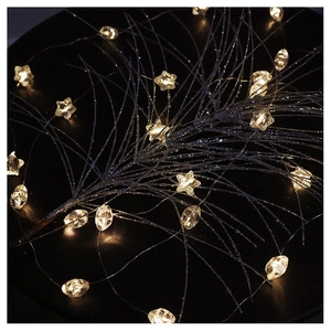 Detail of warm yellow LED star and diamond crystal string lights on dark branches