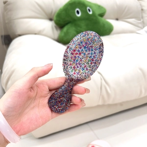 Close-up of a portable transparent resin hairbrush filled with colorful glitter flakes