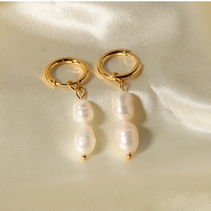 Detailed macro of gold hoop earrings with natural baroque pearls on beige silk