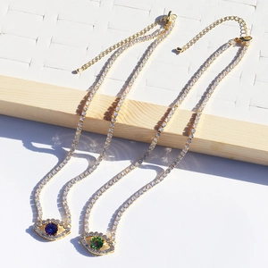 Close-up of gold evil eye pendants with blue and green stones on sparkling tennis chains
