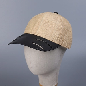 Close-up of raffia straw baseball cap with black leather brim and hollowed-out details