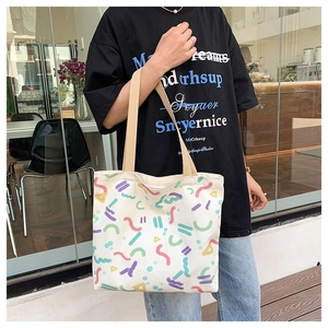 Detail of white canvas tote bag featuring colorful abstract geometric print and beige straps