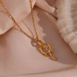 Macro shot of 18K gold plated lava drop pendant on a fine cross chain over pink silk