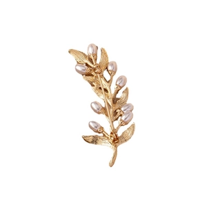 Back view of a gold leaf brooch with pearls and metal pin closure on white background