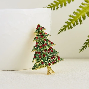 Close-up of a Christmas tree brooch with green enamel and red rhinestones on a ceramic cup