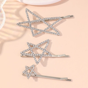 Close-up of three silver star hair clips featuring sparkling rhinestones on a beige backdrop