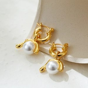 Macro detail of vintage gold earrings with detachable natural pearls on stone surface