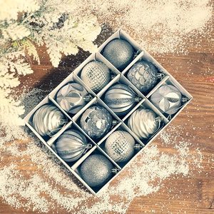12-piece silver Christmas ball ornaments set with diverse textures in a grid display box