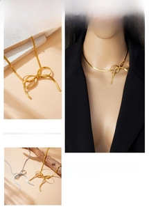 Detail view of gold and silver bow snake chain necklaces with sleek metallic finish