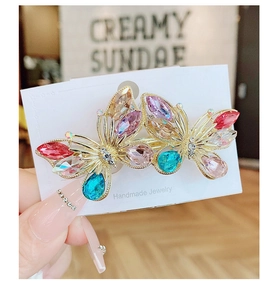 Macro detail of handmade gold butterfly hair clip with colorful crystal embellishments