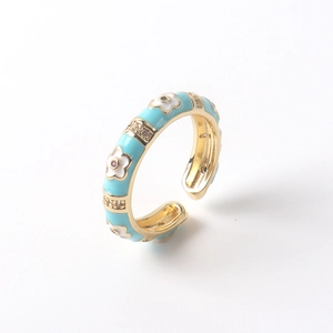 Macro detail of adjustable 18K gold plated ring with light blue enamel flower and zircon