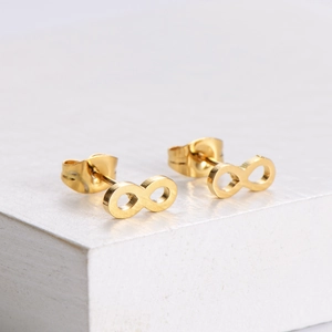 Golden infinity symbol stud earrings in titanium steel on minimalist stone surface