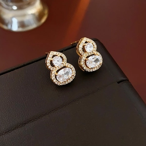 Detailed close-up of gold-plated gourd stud earrings with sparkling cubic zirconia stones