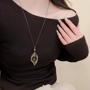 Detail of tiger eye stone pendant with gold leaf filigree on a long woven necklace
