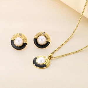 Dettaglio della collana a catena dorata ritorta e orecchini di perle su tessuto beige pregiato