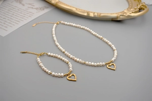 Flat lay of freshwater pearl jewelry set with gold heart pendant and lobster clasp