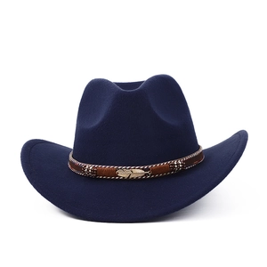 Détail d'un chapeau en feutre bleu marine avec bandeau tressé marron et épingle plume dorée