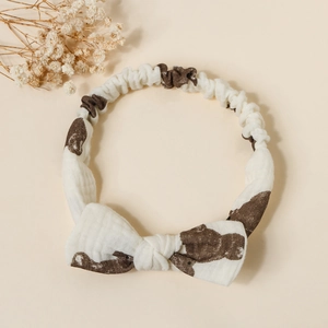 Close-up of baby cotton bow headband featuring brown bear patterns on creamy white fabric