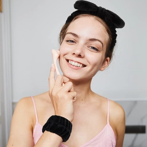 Detail showing soft pink skincare headband and matching wristbands for face washing routine