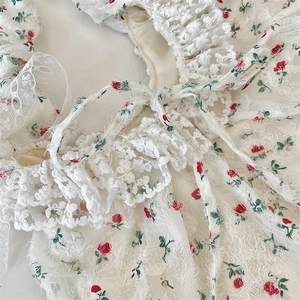 Detail of floral lace tote bag with red rose embroidery and romantic pleated shoulder strap