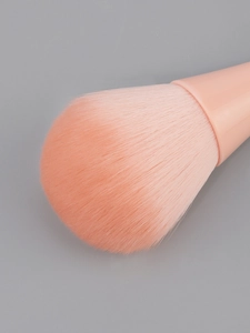 Detailed close-up of fluffy peach pink powder brush bristles with dense synthetic fiber