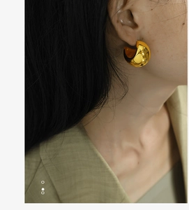 Close-up of polished gold chunky C-shaped hoop earring worn by a model for a chic look