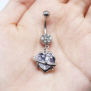 Macro shot of a silver heart-shaped belly ring featuring clear gemstones held in hand