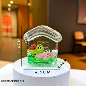 Detail shot showing house-shaped liquid keychain with floating turtle and pink petals