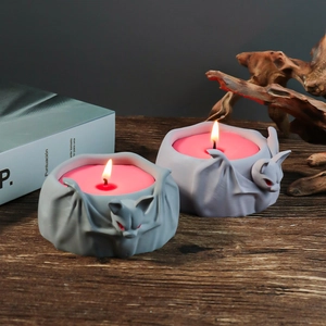 Gothic bat candle holder with gray stone texture and red eyes lit with warm candlelight
