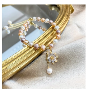 Detail of freshwater pearl bracelet with zircon sunflower charm on vintage gold mirror