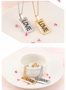 Macro view of gold and silver square pendants with LOVE engraving on O-link chains