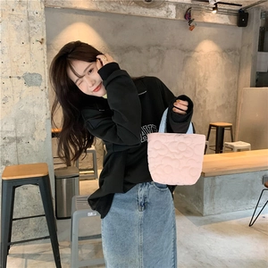 Casual lifestyle shot of a pink quilted tote bag with floral texture and top handles