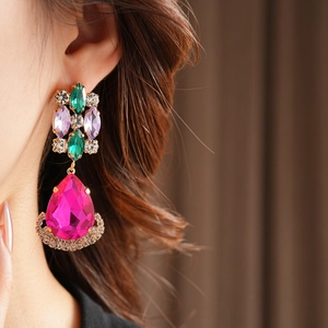 Detailed close-up of vintage drop earrings with colorful crystals on model