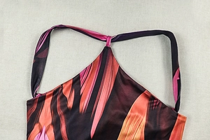 Detail of halter neck neckline with vibrant abstract orange and red silk print pattern