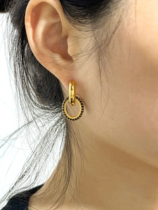 Détail de boucles d'oreilles en or 18K avec anneau de zircons noirs sur l'oreille