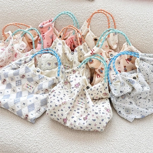Detail of quilted cartoon puppy handbags in pastel pink and blue with sozakka branding
