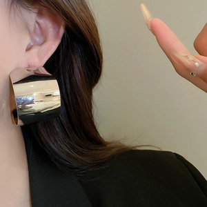 Macro side view of large silver polished C-shaped hoop earring worn on a model's ear