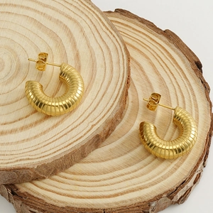 Chunky gold-plated stainless steel twisted U-shaped hoop earrings on wood