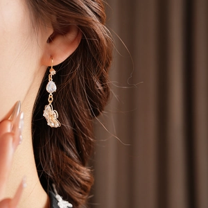 Macro detail of gold flower drop earrings with zircon stone and butterfly pendant