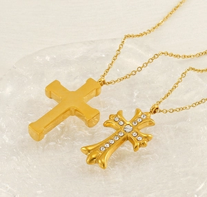 Detail of two gold cross necklaces including one smooth and one gothic zircon-set design