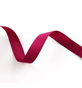 Macro shot of wavy dark red double-sided satin ribbon with glossy texture on white background