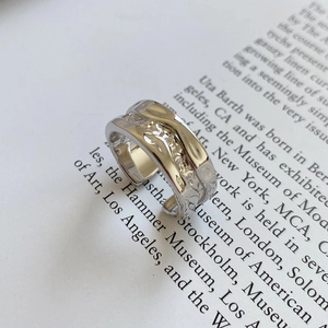 Macro view of wide irregular wave texture silver ring on an artistic paper background